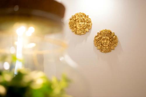 two gold wall hooks with faces on a wall at Il Moro di Ossuna in Trapani