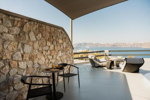 a patio with a table and chairs and a stone wall at Black Diamond Suites in Akrotiri