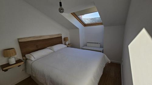 une chambre avec un lit blanc et une fenêtre dans l'établissement Apartamento a estrenar Mar de Cunchas, à San Martín de Arriba