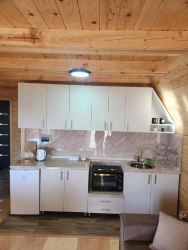a kitchen with white cabinets and a microwave at ROMANIJA 2-Brvnara za odmor in Han Pijesak