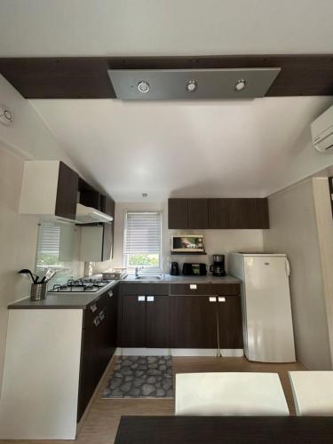 a kitchen with brown cabinets and a white refrigerator at mobil home AU SOLEIL in La Roque-dʼAnthéron