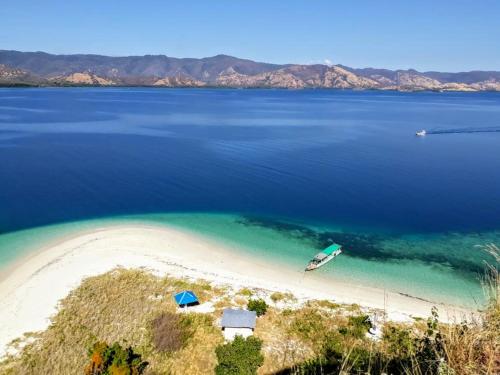 an aerial view of a beach with a boat in the water at All-Inclusive Paradise Experience - Boat Tour, Snorkeling & Island Camping 