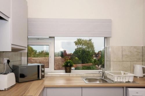 a kitchen with a window and a sink and a microwave at 33 Beautiful 2 bed apt Tamworth Private Parking in Fazeley