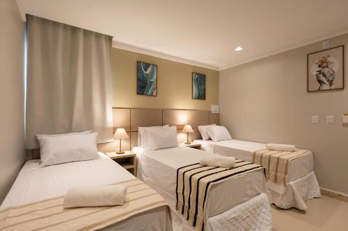 a room with three beds and two tables at Aira Hotel in Sobral