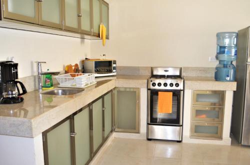 Arrecifes Suites في بويرتو موريلوس: مطبخ بخزائن خضراء وموقد الفرن العلوي