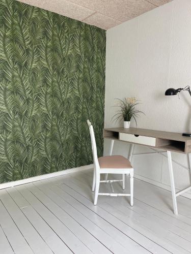 escritorio y silla en una habitación con una pared verde en The Farm Managers House at Hindemae Estate Historic Charmed house, en Ullerslev