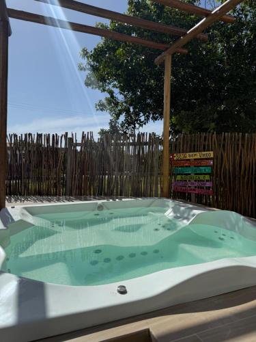 a hot tub in a backyard with a wooden fence at Paraíso dos Lençóis casa 08 Atins in Atins