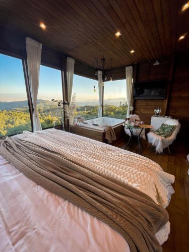 une chambre avec un grand lit avec une grande fenêtre dans l'établissement Top Cabana Romântica Serra Catarinense - Anitápolis SC, à Annitapolis