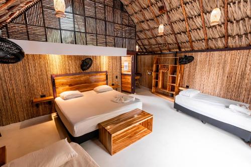 a bedroom with two beds and two tables in it at La Playita Isla Fuerte in Isla Fuerte