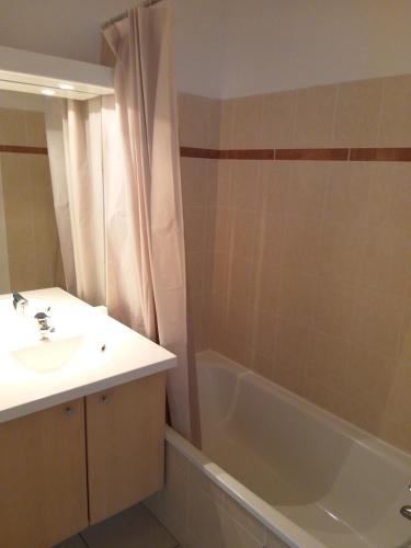 une salle de bain avec un lavabo et une baignoire dans l'établissement Appartement dans résidence standing piscine, tennis, à Perpignan