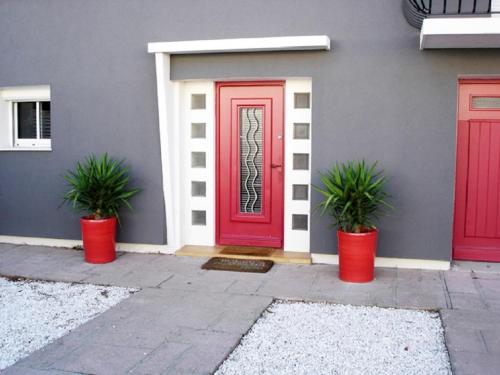 une porte rouge avec deux plantes en pot devant une maison dans l'établissement Villa Orane, à Argelès-sur-Mer