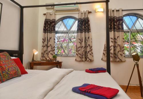 two towels on a bed in a bedroom with windows at You are the key Villa in Anjuna