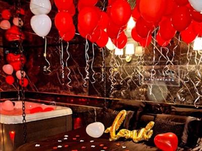 un bouquet de ballons rouges et blancs suspendus au-dessus d'une table dans l'établissement Suite avec jacuzzi, à Montpellier