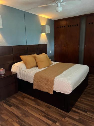a bedroom with a large bed with white sheets and yellow pillows at Loft con vista al lago in Querétaro