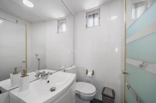 a white bathroom with a toilet and a sink at Sea Hut Apulia in Apúlia