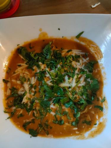 a bowl of soup with cheese and greens on it at La maison in Gandoca