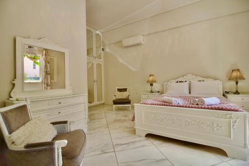 a white bedroom with a bed and a chair at Central Luxurious Retreat in Argostoli