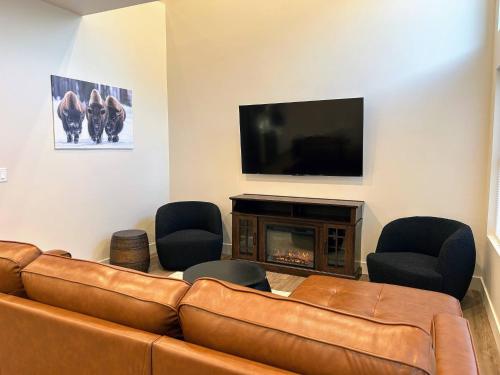 a living room with a leather couch and a fireplace at Teton Duo | Side-by-Side Homes | Hot Tubs+Walkable in Driggs