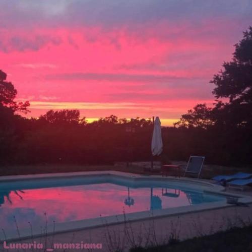 a sunset over a swimming pool with a umbrella at Lunaria Manziana in Sambuco