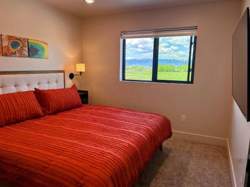 a bedroom with a red bed and a window at Teton Duo | Side-by-Side Homes | Hot Tubs+Walkable in Driggs