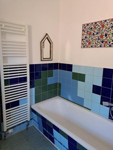 a bath tub in a bathroom with blue and green tiles at Haus an der Stadtmauer in Lychen