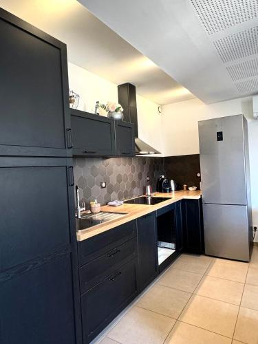 une cuisine avec des armoires noires et un réfrigérateur en acier inoxydable dans l'établissement appartement hyeres centre, à Hyères