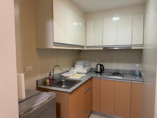 a small kitchen with white cabinets and a sink at Cozy Condo in Megaworld Iloilo in Iloilo City