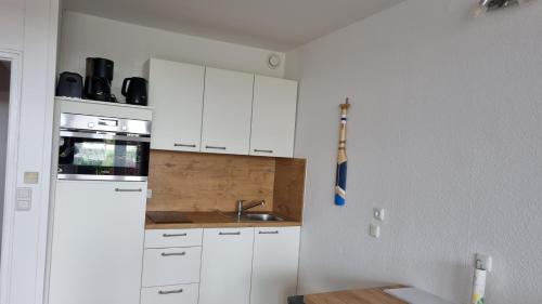 a kitchen with white cabinets and a sink at Optimist Sunlife Ostsee in Wendtorf