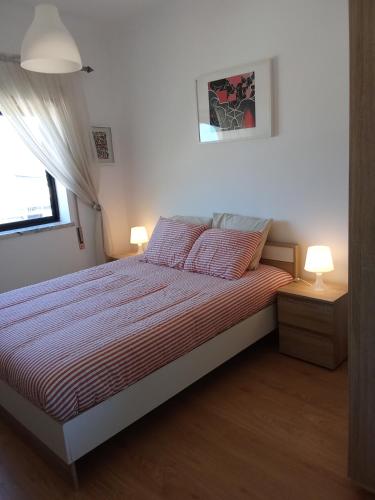a bedroom with a bed with two lamps and a window at Apartamento Abibinho in Figueira da Foz