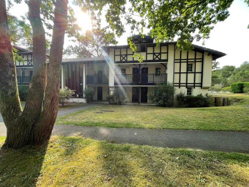 a house with a tree in front of it at Joli appartement au golf in Biscarrosse