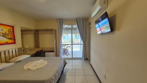 a bedroom with two beds and a television on the wall at Pousada Ceará - Porto das Dunas in Aquiraz