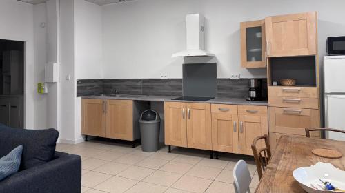 - une cuisine avec des placards en bois et une table dans une pièce dans l'établissement Appartement T2 à proximité du Salagou, à Clermont-lʼHérault