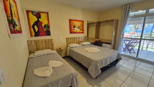 a hotel room with two beds and a window at Pousada Ceará - Porto das Dunas in Aquiraz