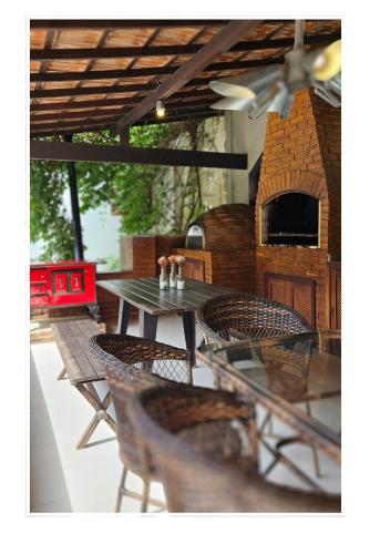 a table and chairs on a patio with a pizza oven at Jardim Secreto - Itaipava in Itaipava