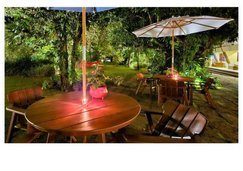 a wooden table and chairs with umbrellas on a patio at Jardim Secreto - Itaipava in Itaipava