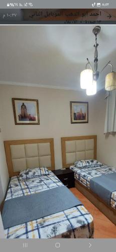 a bedroom with two beds and a light on the wall at Porto marina luxury flat for families onlyشاليه فاخرداخل بورتو مارينا in El Alamein