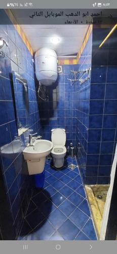a blue tiled bathroom with a toilet and a sink at Porto marina luxury flat for families onlyشاليه فاخرداخل بورتو مارينا in El Alamein