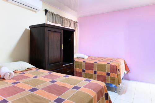 a bedroom with two beds and a cabinet and purple walls at p Apartamentos Petenchel, por Aeropuerto Flores Peten 1 in Flores