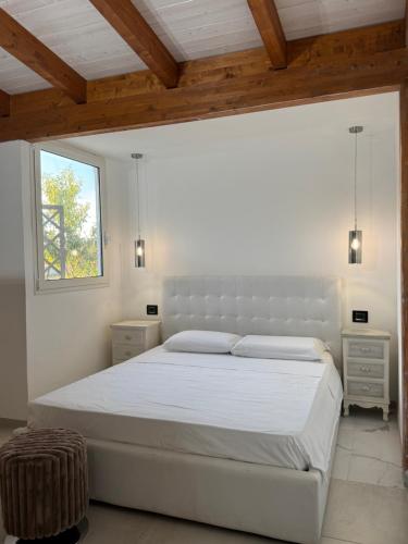a bedroom with a large white bed with a window at Casa di Raf in Torre Lapillo