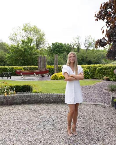 a woman in a white dress standing in a park at Fitz Of Inch in Stradbally