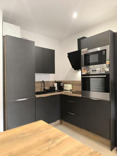 une cuisine avec des armoires noires et un four micro-ondes dans l'établissement Hyper Centre de Nice - Agréable 3 pièces, à Nice