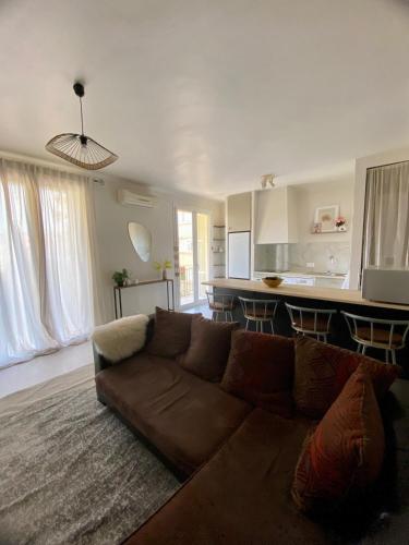 un salon avec un canapé marron et une cuisine dans l'établissement Superbe T2 refait à neuf, tout équipé, très lumineux, au calme ! Parking privé - Ajaccio, à Ajaccio