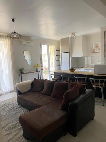 un salon avec un canapé marron et une cuisine dans l'établissement Superbe T2 refait à neuf, tout équipé, très lumineux, au calme ! Parking privé - Ajaccio, à Ajaccio