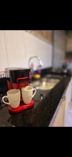 two coffee cups sitting on a red plate on a kitchen counter at Casa Studio 1 Quarto in São José dos Campos