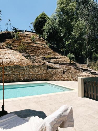 a swimming pool with a chair and an umbrella at A casa da Lomba in Lomba