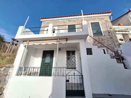 a white house with a green door and stairs at balconi 1911 - Traditional house in Ydroussa, Samos in Ydroússa