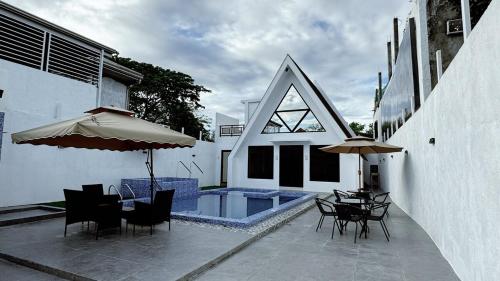a patio with chairs and an umbrella and a pool at The Prism Cabin - Private Resort in North Caloocan Philippines in Camarin