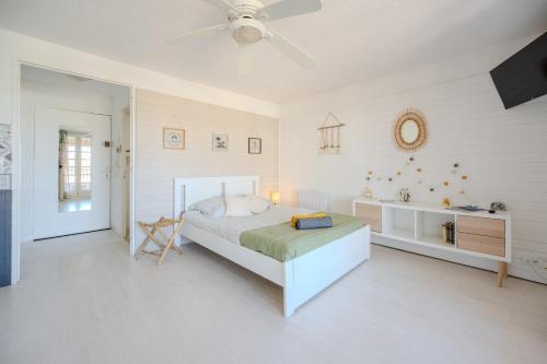 une chambre blanche avec un lit et un ventilateur de plafond dans l'établissement Studio Horizon Sablettes, à La Seyne-sur-Mer