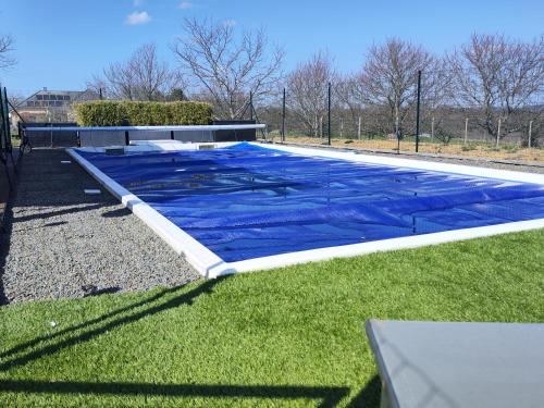 - une piscine bleue dans une cour avec gazon dans l'établissement Maison avec piscine, à Troche