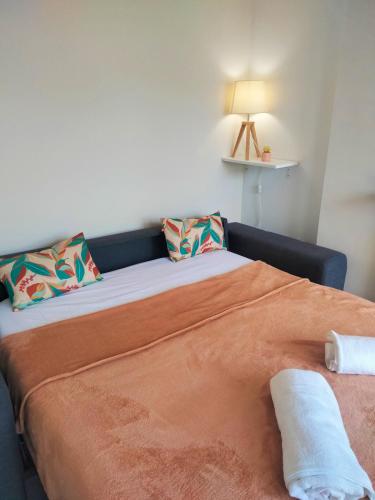 - un lit avec des draps et des oreillers orange dans l'établissement Appartement Bord de mer, à Hyères